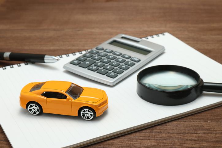 Toy car, magnifying glass, calculator, pen and notebook.